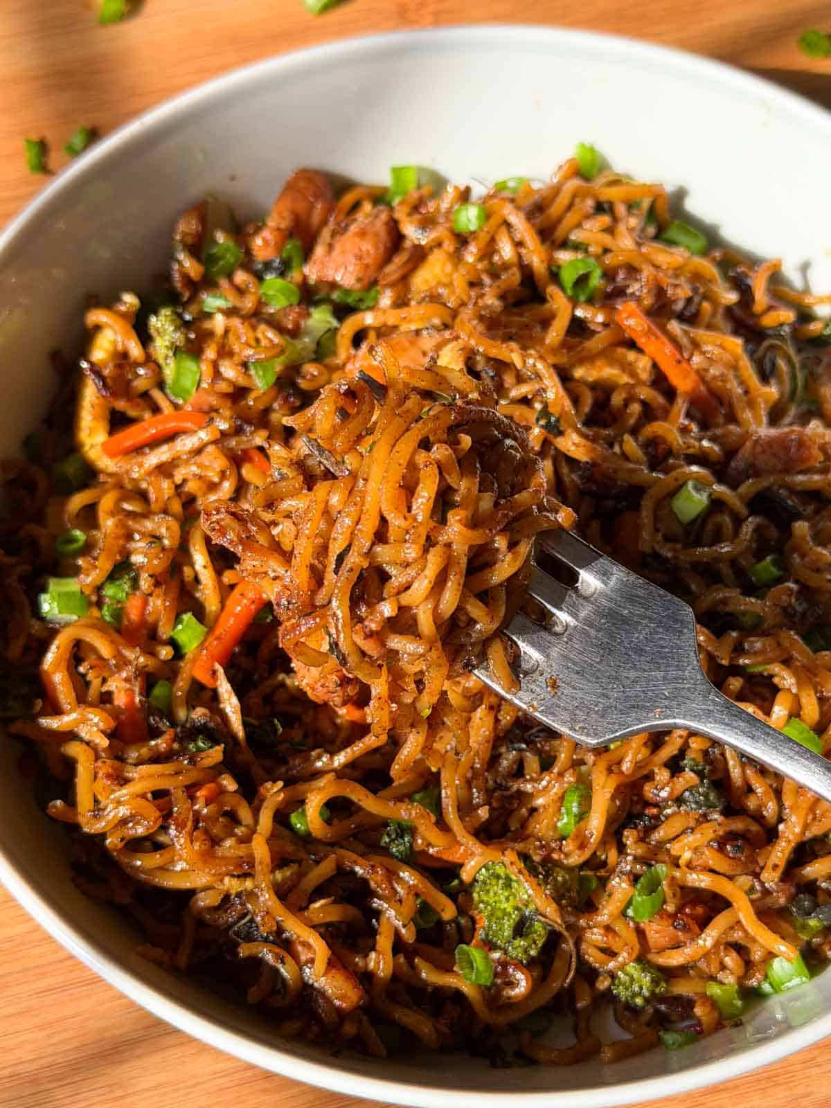 Thai drunken noodles in a white serving bowl with spoon