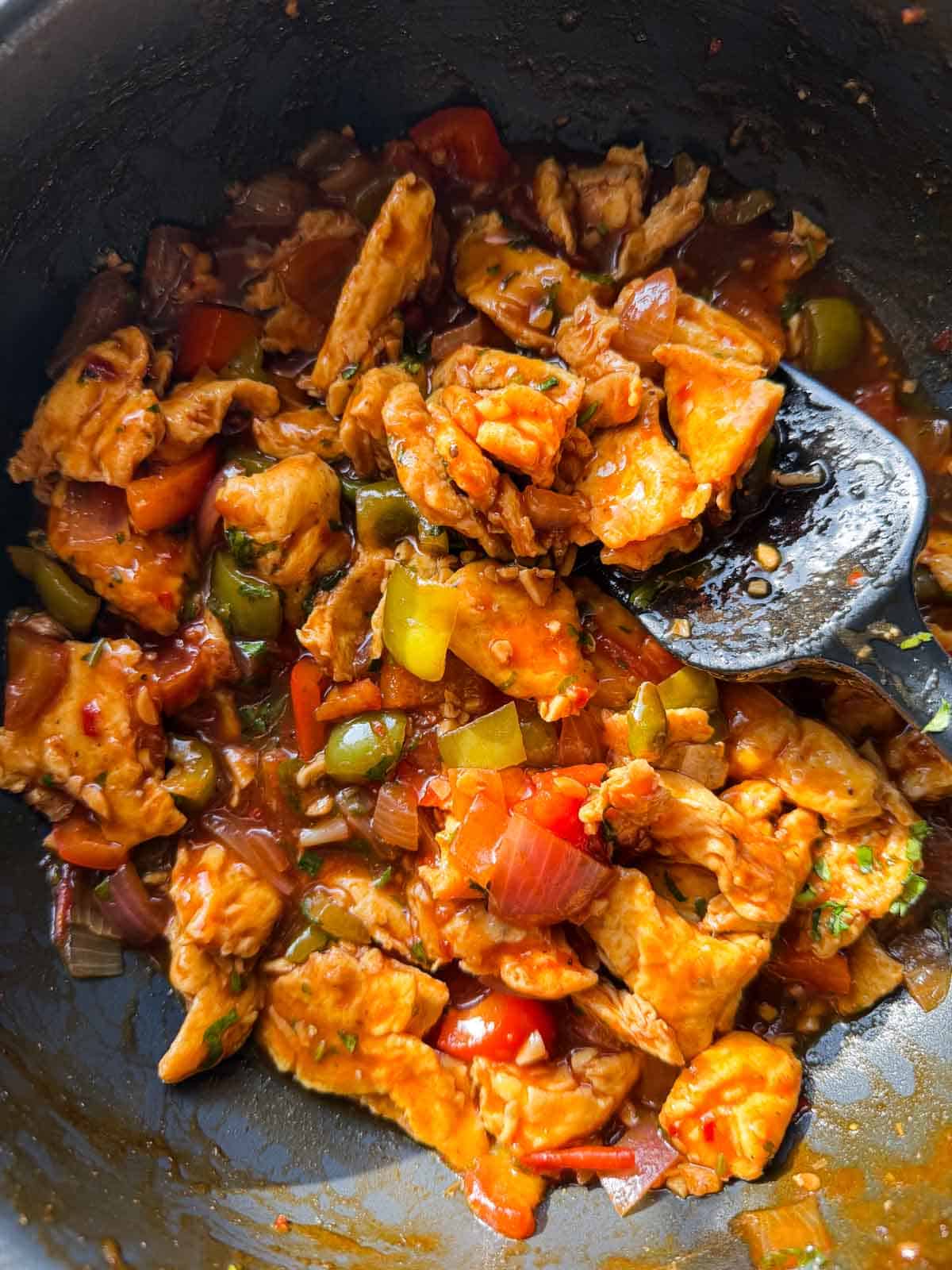 chilli egg stir fry in its cooking pan with ladle