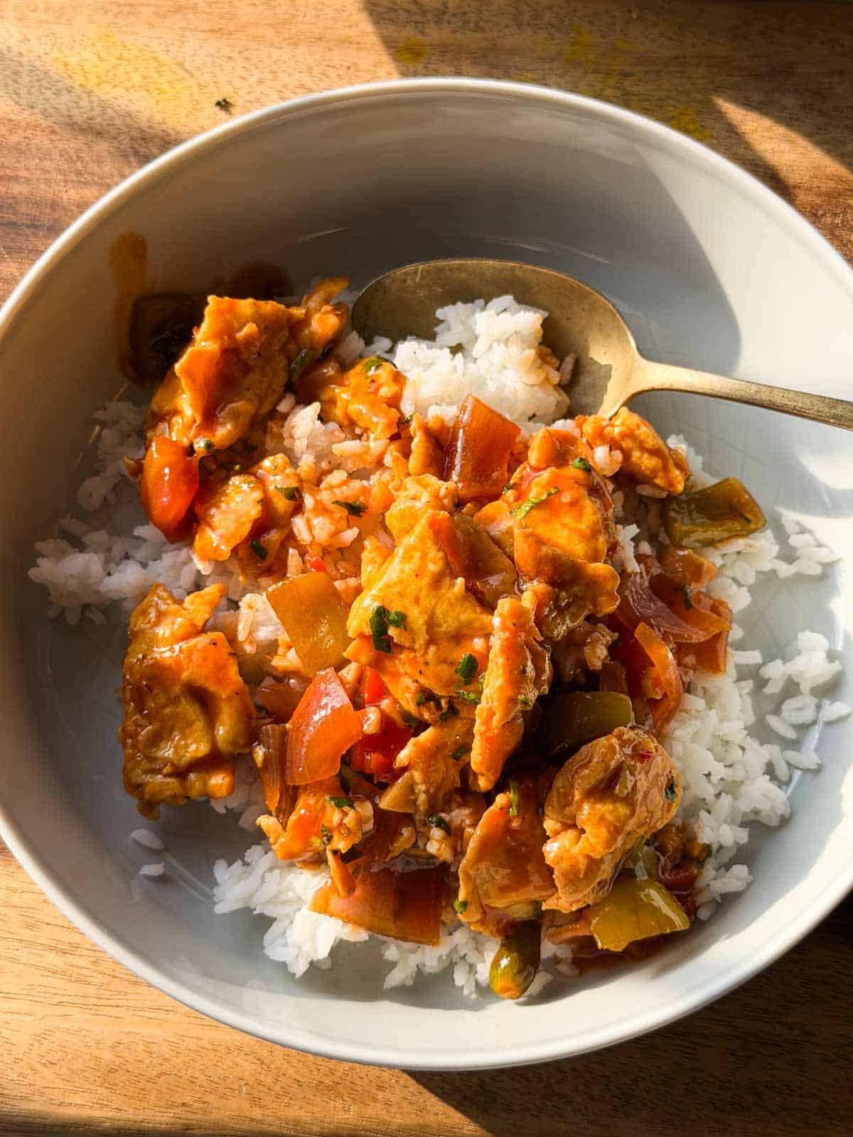 chilli egg stir fry in a white bowl with spoon