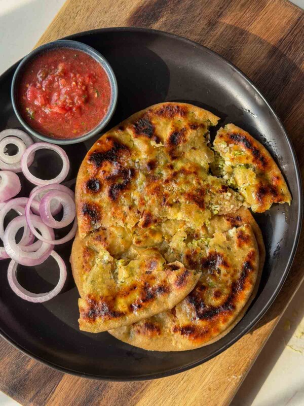 broccoli paneer paratha served on a black plate with accompaniments