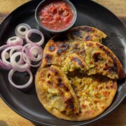 broccoli paneer paratha served on a black plate with accompaniments