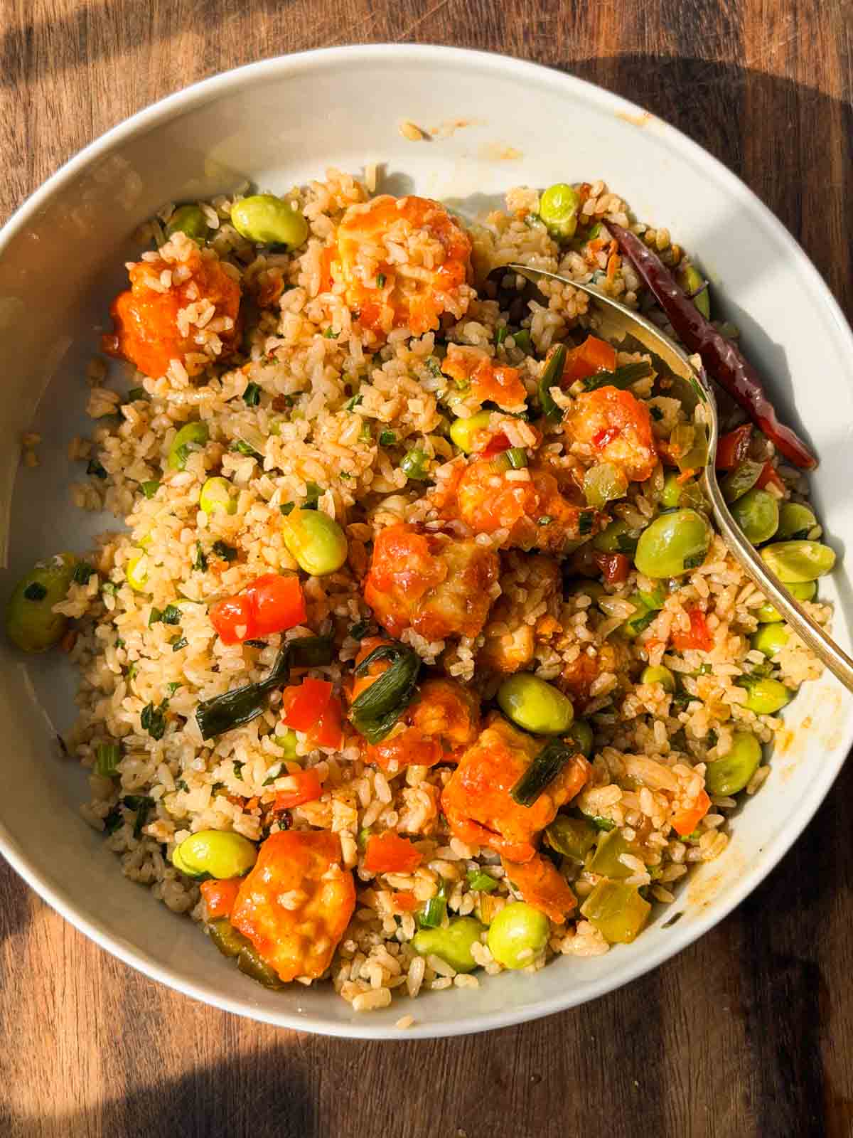 edamame garlic rice topped with teriyaki chicken and served in a white bowl