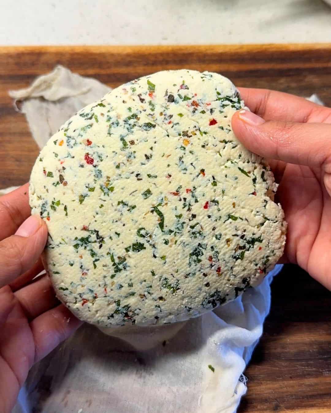 a person holding a slab of freshly made herbed paneer