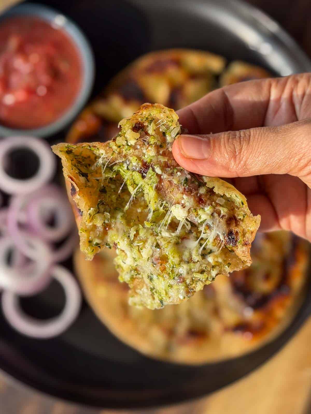 a person holding an opened broccoli paratha to showcase it's the stuffing inside