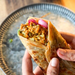 a person holding an assembled masala egg roll
