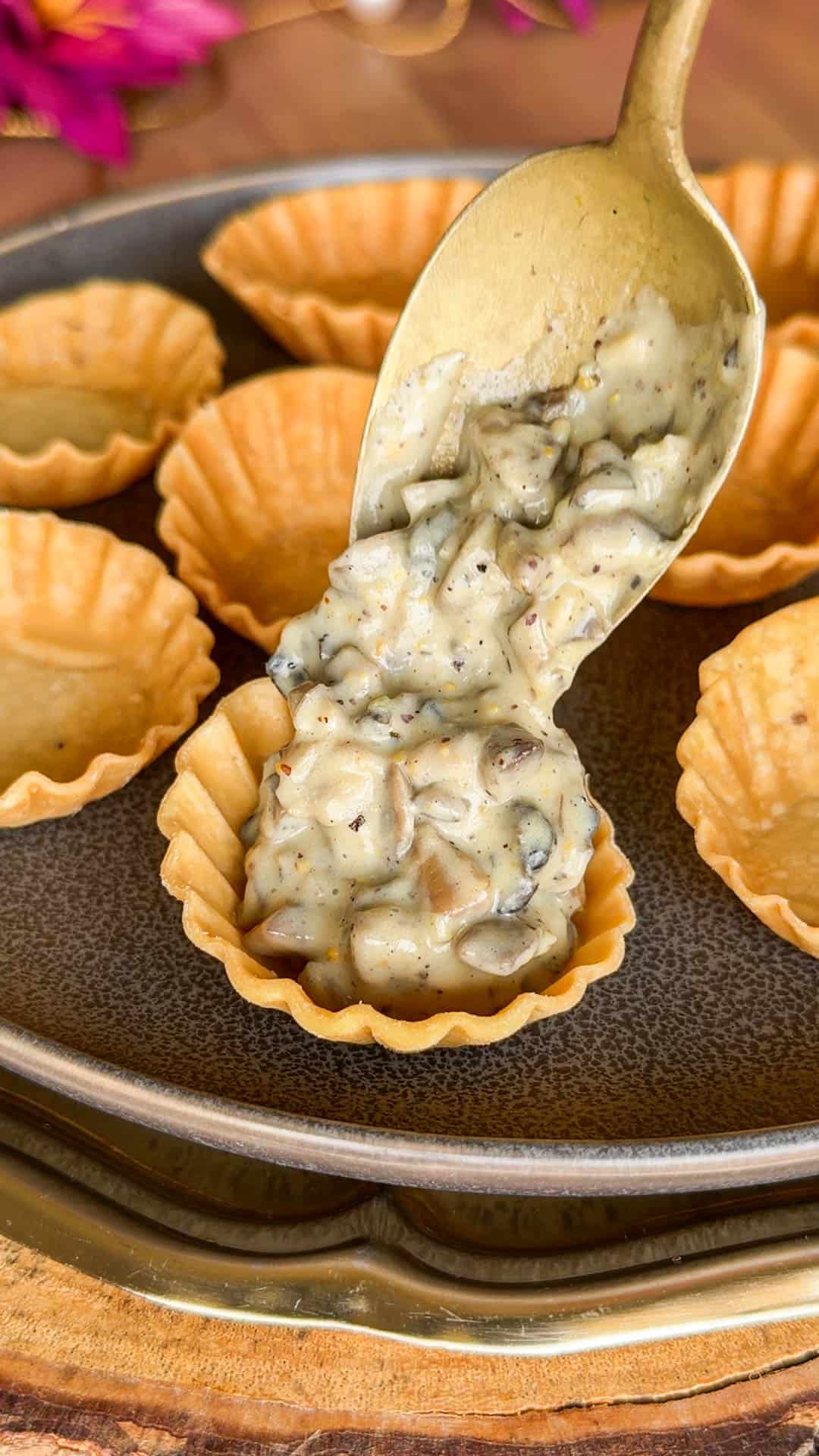a person adding the mushroom filling to the tarts