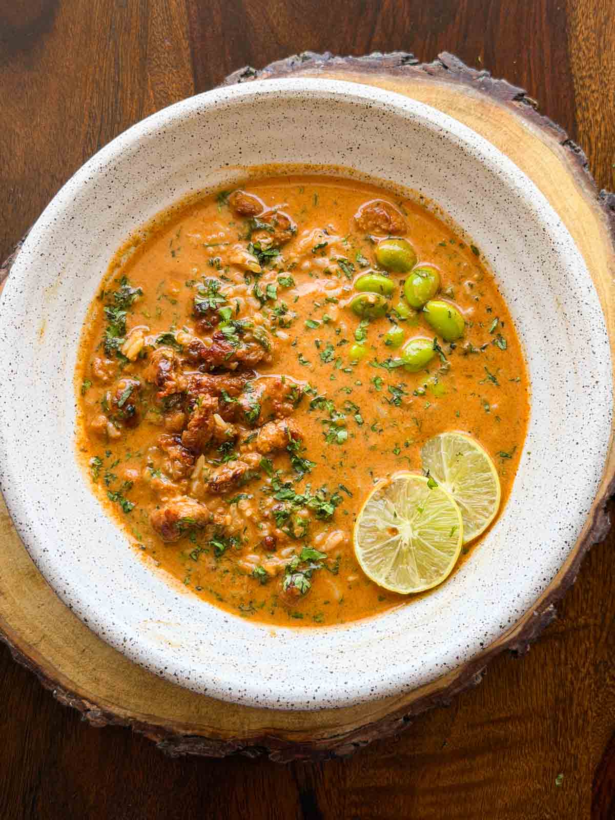 spicy chicken and rice broth bowl served in a white bowl with lemon slices