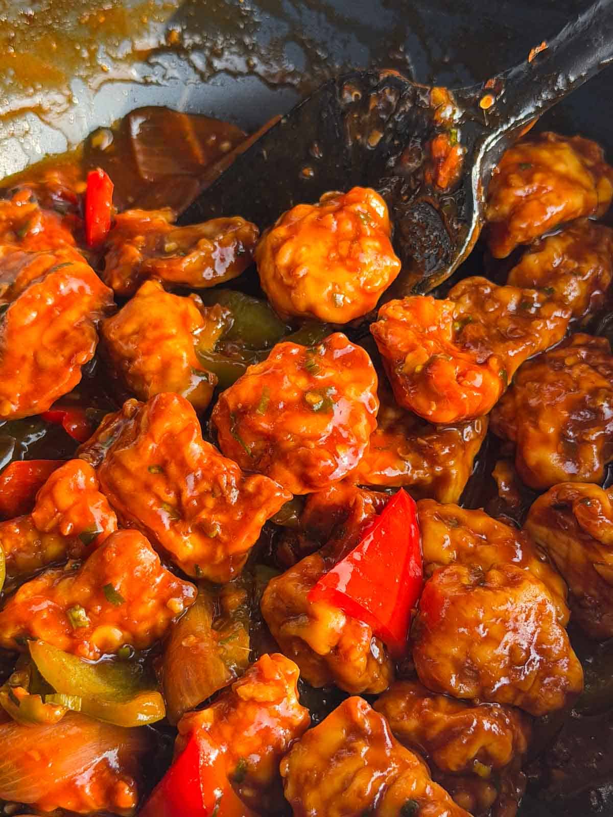 a close up image of chilli chicken in the wok